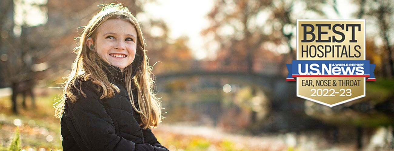 young girl with hearing aid smiling outside