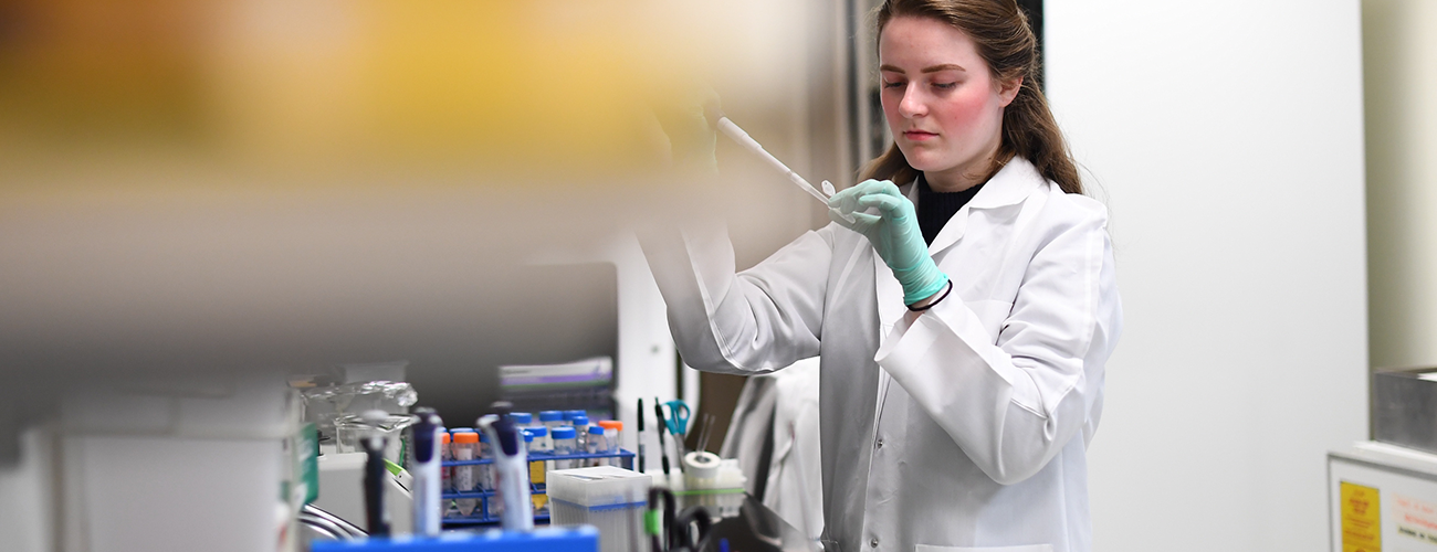 researcher piping liquid in a vial at a lab