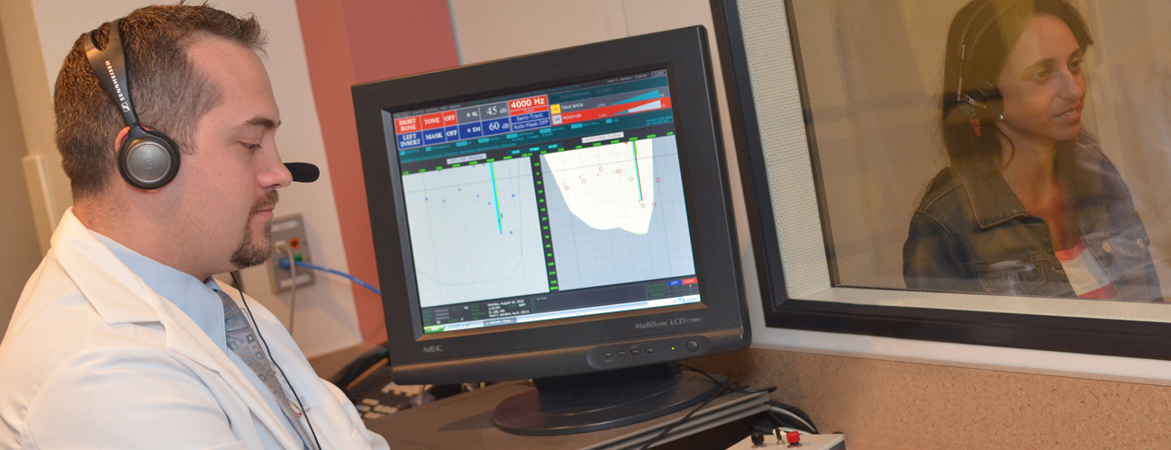 audiologist performs a hearing test on a patient