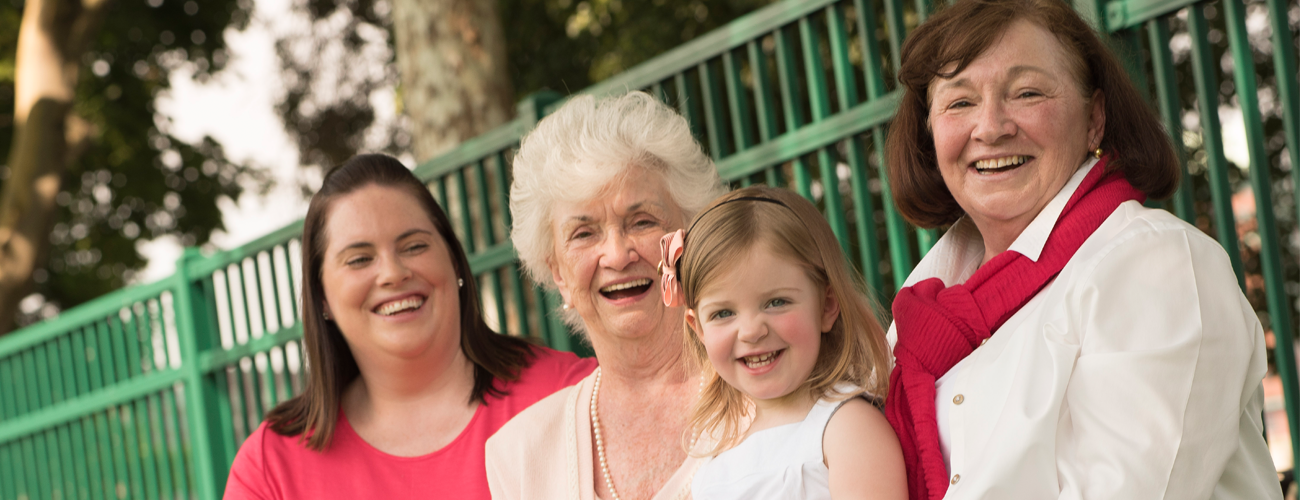 four generations of women sitting outside on a bench