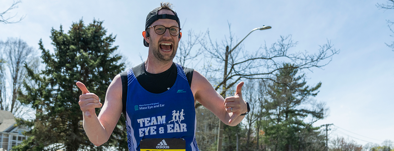 team eye and ear marathon male runner smiling while giving a thumbs up