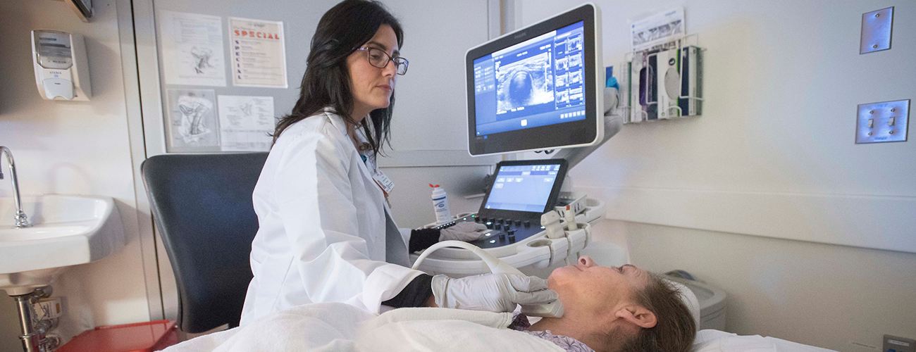 imaging technician performing a neck ultrasound on a patient in an exam room