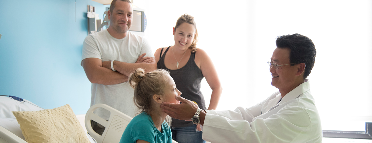 physician examines pediatric patient with family members nearby