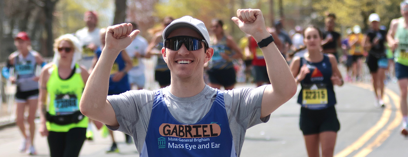 team eye and ear marathon male runner smiling with his hands in the air